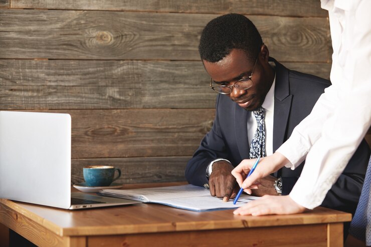 focused-african-american-businessman-checking-papers-with-his-personal-assistant-white-shirt_273609-13575